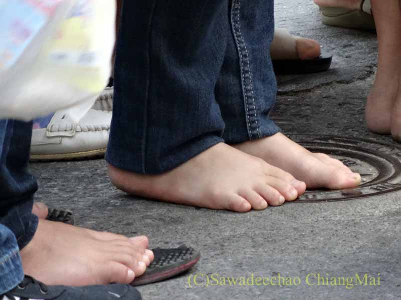 チェンマイの元旦の特別タムブンで僧侶に供養するために列を作る人々の足